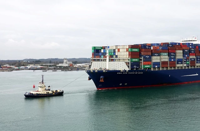 Container ship towed by tiny tugboat